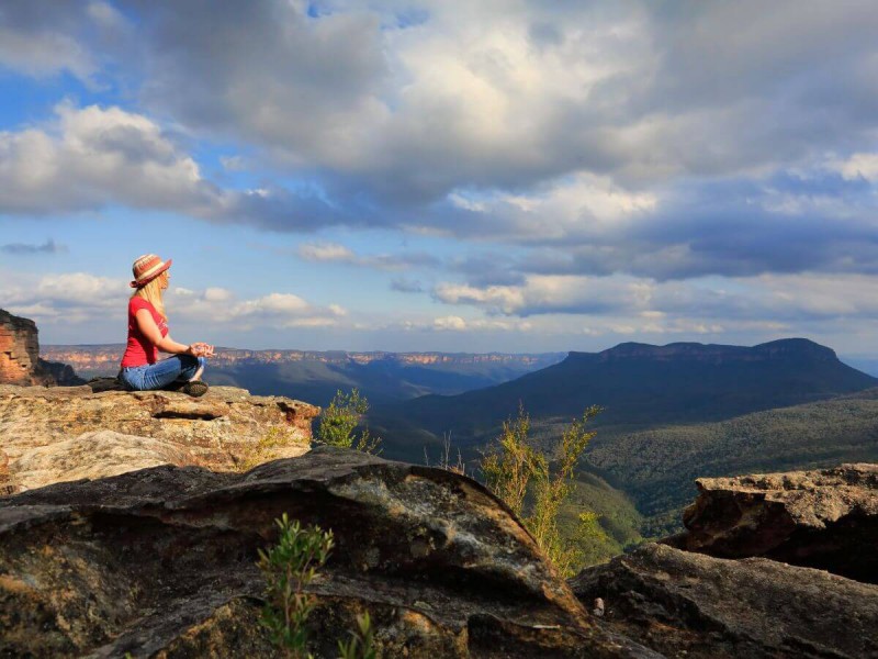 Žena medituje při krásném skalnatém výhledu v Blue Mountains nedaleko Sydney.