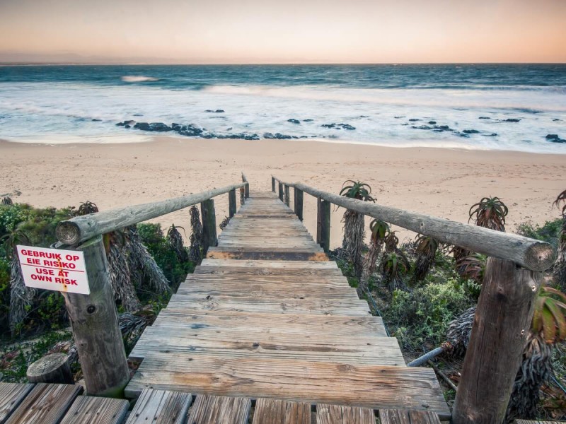 Vstup po dřevěných schodech na pláž v Jeffreys Bay.