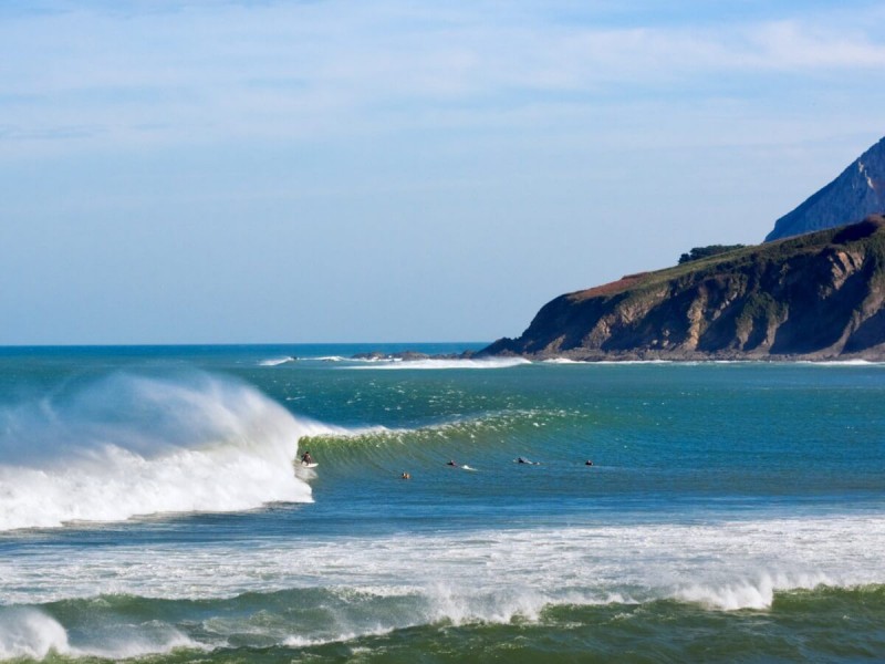 Surfaři jezdící vlny na španělském pobřeží v Mundaka.