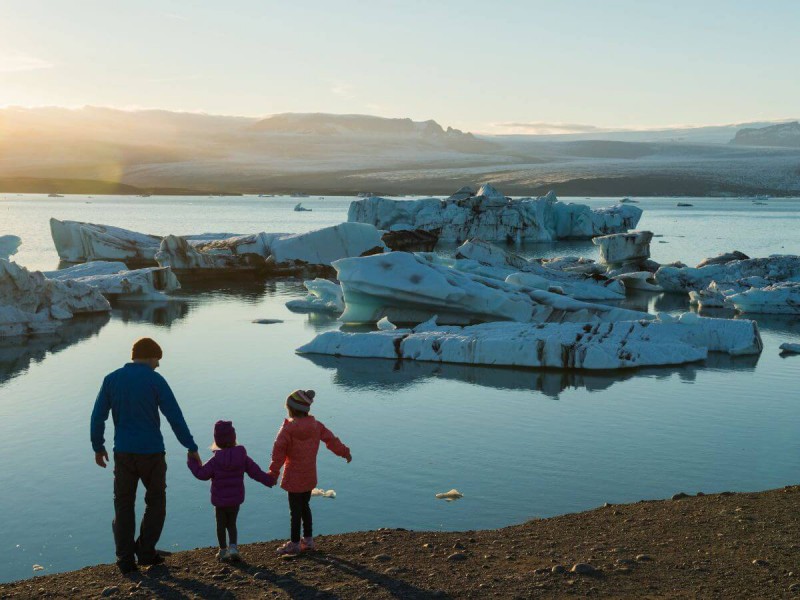 Otec drží za ruku dvě děti v laguně Jokulsarlon na Islandu.