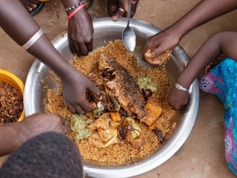 Společné pojídání typického senegalského jídlo Thieboudienne.